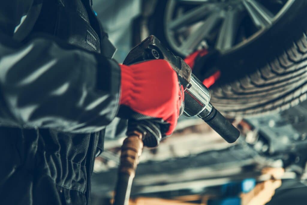 Seasonal Car Wheels Replacement. Car Mechanic with Power Tool Inside the Auto Service. Tire Rotation and Wheel Alignment